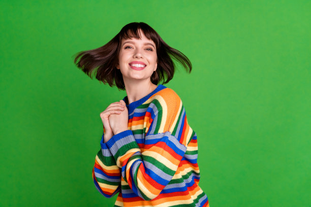 照片：一位迷人的年轻女子，头发被风吹起，孤立在绿色背景上图片下载