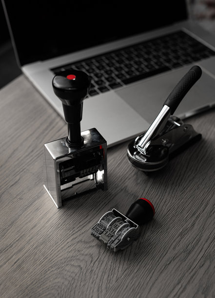 桌上的金属办公印章，背景是笔记本电脑 - 竖幅照片图片下载