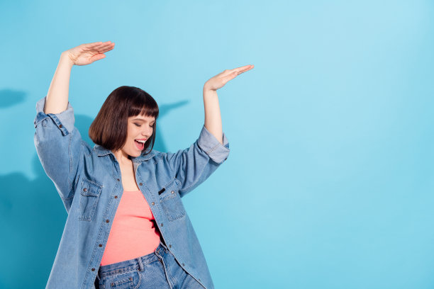 一位迷人的、快乐的、酷炫的女孩的肖像，她在明亮的蓝色背景上跳舞、玩乐，并留有空白空间。图片下载