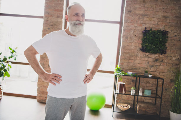 照片：一位快乐、微笑、心情愉悦、梦想家般英俊、成熟、留着胡须的男人在家中艰苦训练后放松图片下载