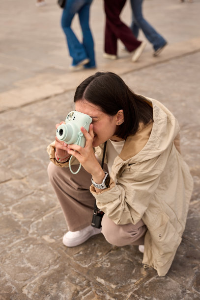 一位女士蹲着，使用拍立得相机拍摄街景照片图片下载