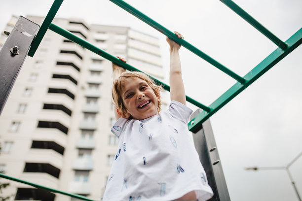 孩子们在儿童游乐场的单杠上大笑的生活方式照片。儿童进行体育活动。可留白。图片下载