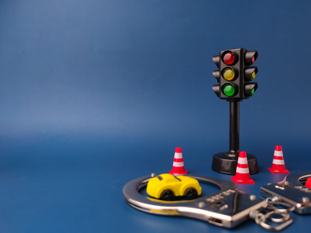 图片展示了一个微型交通信号灯、一辆玩具车、一副手铐和几个交通锥，背景为蓝色。图片下载