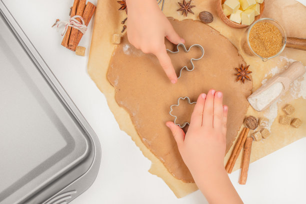 孩子们用金属饼干模具从面团中切割姜饼，俯视角度，节日圣诞烘焙准备，包含食材和烤盘图片下载