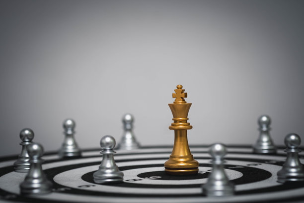 金色棋子国王位于飞镖盘上，周围环绕着兵卒，象征着领导力、目标设定和战略重点。非常适合商业、团队建设和高管概念。图片下载