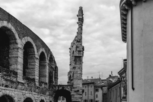 维罗纳圆形剧场的单色照片捕捉到了罗马砖石和拱门与城市建筑并存的景象，反映了古今维罗纳的共存。图片下载