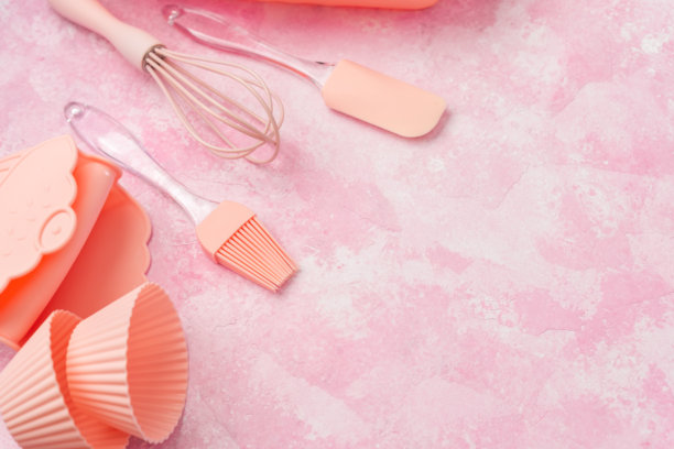 粉色墙壁背景上的纸杯蛋糕硅胶模具和粉色烘焙用具图片下载