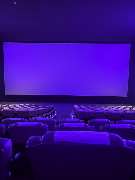 一个一尘不染的电影院大厅，拥有成排的豪华蓝色座椅、一个宏伟的、灯光璀璨的屏幕以及柔和的环境照明，营造出一种引人入胜的、为下一批观众准备的氛围。图片下载