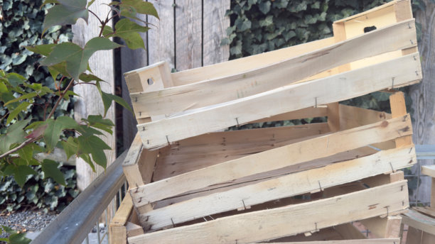 阳光下，植物旁的空木箱堆叠，这些天然的储物箱可用作园艺或运输蔬菜。专业照片图片下载