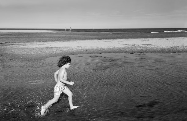 男孩在海滩上奔跑，黑白照片图片下载
