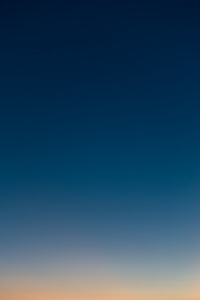 绝美的晴朗无云的傍晚天空的竖直照片。天空从橙色渐变到深蓝色。图片下载