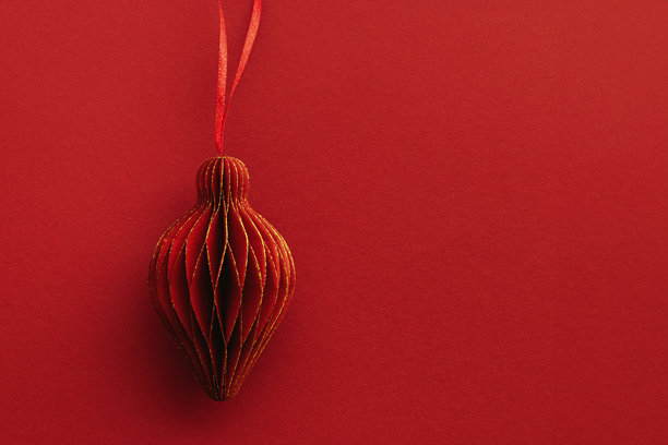 节日红色纸质圣诞装饰品，悬挂的红色手电筒或灯笼，红色背景上的蜂窝斯堪的纳维亚装饰，极简单色照片，温暖喜庆的节日气氛，俯视角度，留有空白空间图片下载