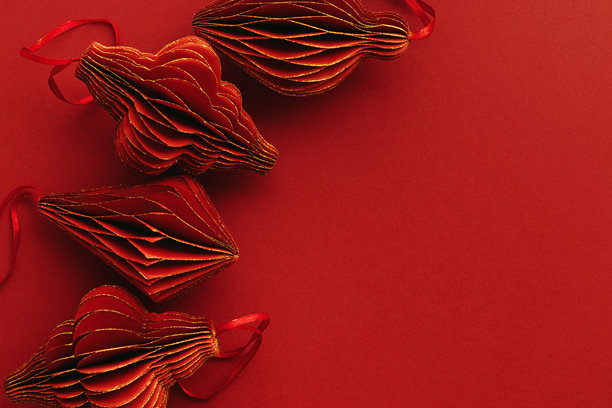 喜庆的红色纸质圣诞装饰品，一排排悬挂的红色手电筒或灯笼，红色背景上的蜂窝状斯堪的纳维亚装饰，极简单色照片，节日氛围俯视，可留白图片下载