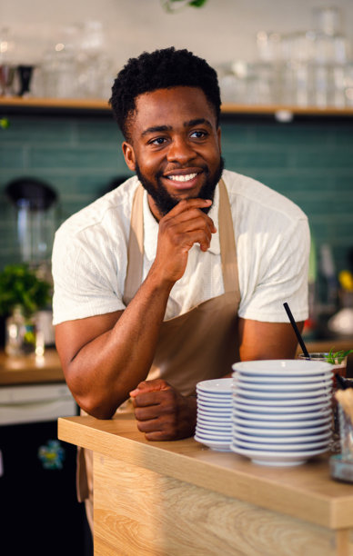 一位非洲裔咖啡师站在咖啡店柜台后面，拍摄肖像照。图片下载