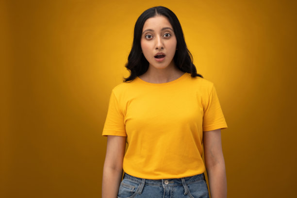 身穿黄色T恤的年轻女子，背景为黄色，隔离拍摄的素材照片图片下载