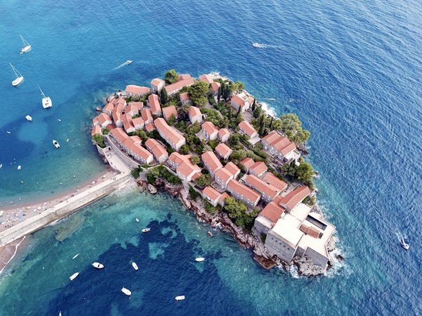 无人机从空中拍摄的圣斯特凡岛、连接岛屿的桥梁以及海中游艇的照片图片下载