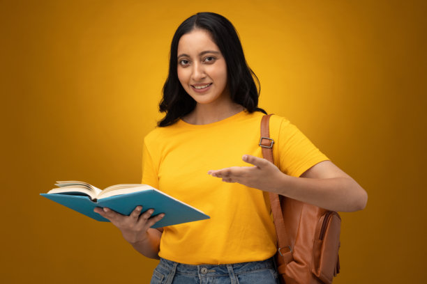 身穿黄色T恤、背着书包的年轻女学生，在白色背景上孤立的素材照片图片下载