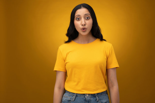 身穿黄色T恤的年轻女子，孤立在黄色背景上的照片素材图片下载