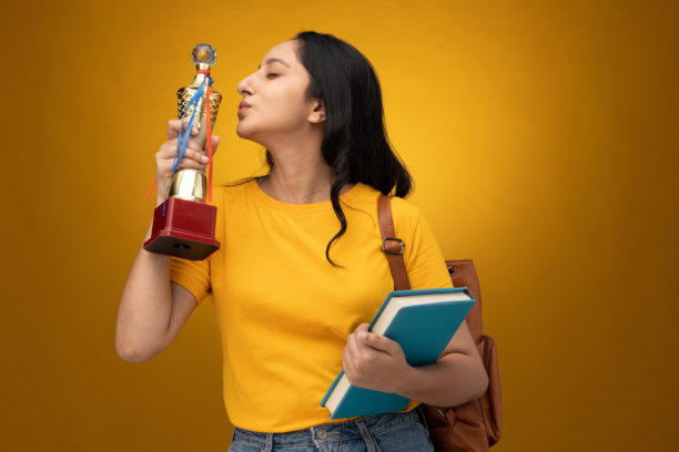 身穿黄色T恤、背着书包和书本的年轻女学生，白色背景下的人物照片素材图片下载