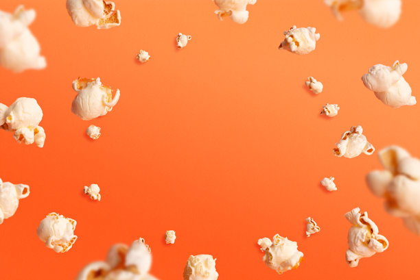 橙色背景上爆米花飞溅的动感照片，简约设计，非常适合零食广告、动态概念或有趣的创意背景图片下载