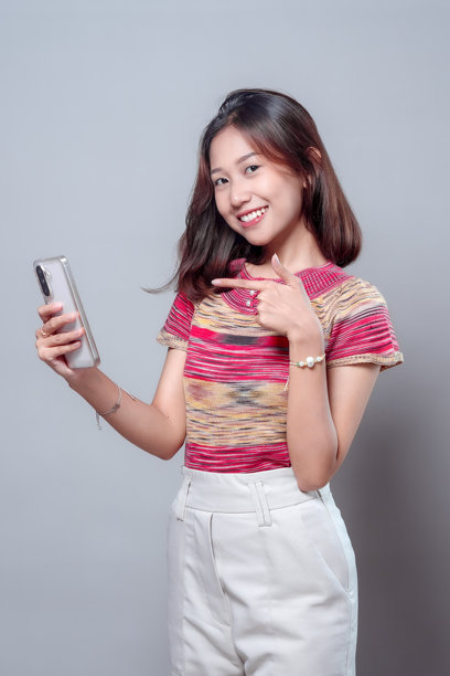 微笑的亚洲女性手指着智能手机屏幕图片下载