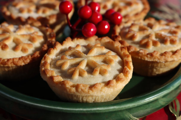 金属托盘上的圣诞肉馅饼和酥皮挞，带有雪花图案，并饰有冬青浆果和节日花环图片下载
