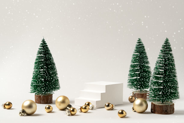 圣诞展示，包含迷你圣诞树、白色阶梯式讲台和散落的金色装饰球，背景为雪景——适用于节日产品和视觉内容的百搭素材。图片下载
