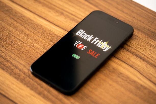 黑色星期五照片。极简风格的黑色星期五标志，手中拿着手机和折扣优惠。适用于黑色星期五促销、广告和社交媒体的横向设计。图片下载