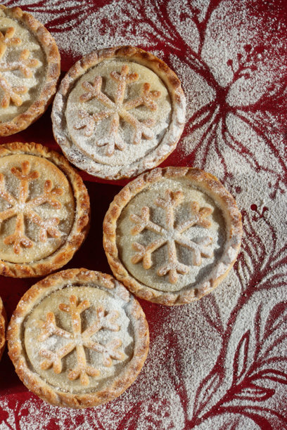 俯视拍摄的节日圣诞肉馅饼，带有精致的雪花酥皮设计，撒上少许糖粉图片下载