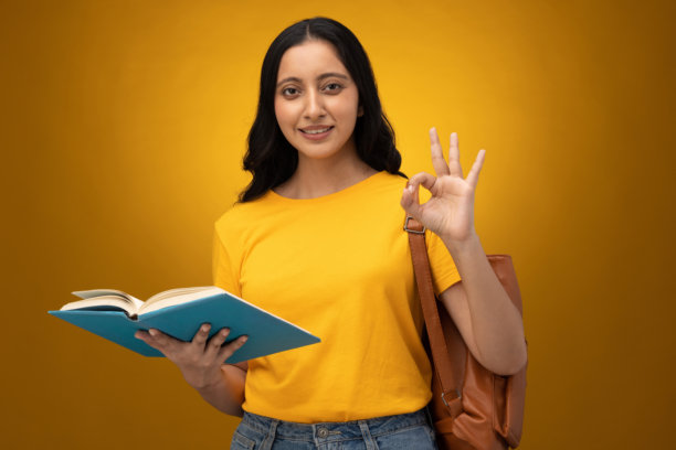 穿着黄色T恤、背着书包、带着书本的年轻女学生，白色背景下的照片素材图片下载