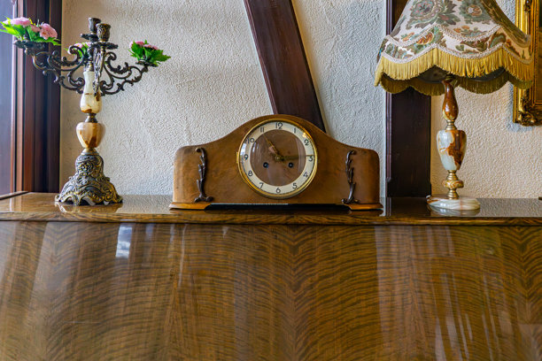 老式木制壁炉钟摆放在餐边柜上，旁边是台灯和烛台，经典复古室内装饰，优雅古董家具家居装饰风格。图片下载