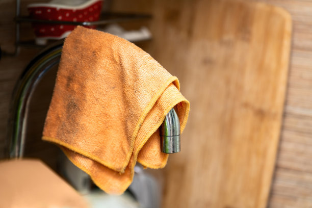 一块橙色的厨房抹布在清洁和擦拭后挂在水龙头上晾干图片下载