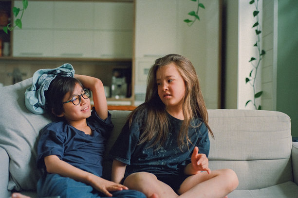 孩子们在家里的沙发上坐着交谈，兄妹或姐弟。胶片照片图片下载