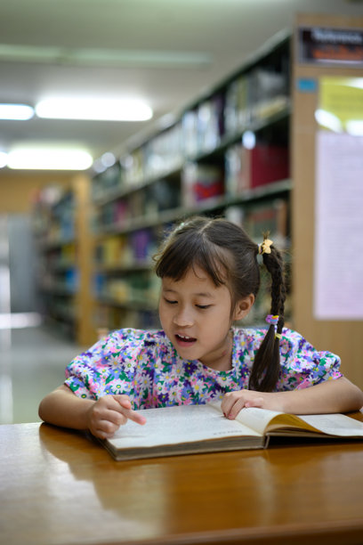 快乐的小女孩在学校图书馆里大声朗读练习册的照片集图片下载