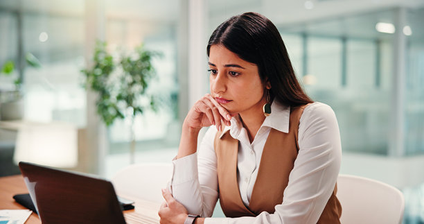 一位职业女性在办公室使用笔记本电脑思考，用于社交媒体、信息沟通或在线研究。该图片描绘了一位女性在工作场所进行网络交流、头脑风暴或获取网络信息时的场景，并伴有想法反馈的元素。图片下载
