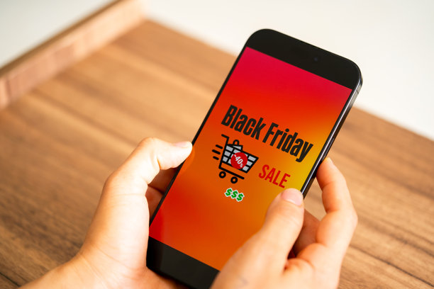 黑色星期五照片。极简主义的黑色星期五符号，手中拿着手机和折扣优惠。适用于黑色星期五销售、广告和社交媒体的横向设计。图片下载