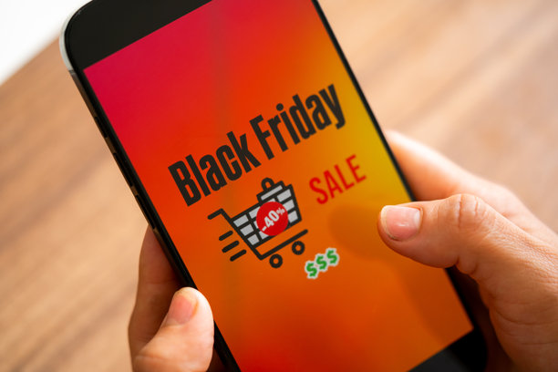黑色星期五照片。极简黑色星期五标志，手中拿着手机和折扣优惠。适用于黑色星期五销售、广告和社交媒体的横向设计。图片下载