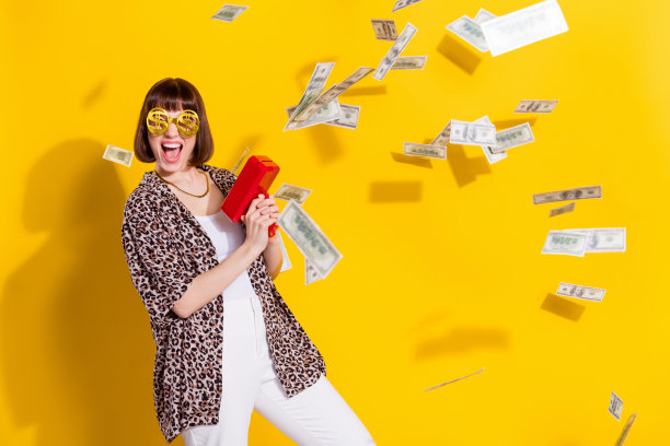 年轻富有的女士戴着眼镜，穿着豹纹衬衫和链子，孤立在黄色背景上，欢呼雀跃地花钱的照片图片下载