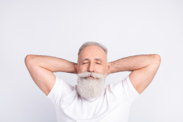 俯视角度拍摄的，头枕着双手，昏昏欲睡、放松的老人，在灰色背景下打盹的照片图片下载