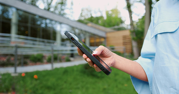 特写镜头，女性手部侧视图，在户外手持并使用智能手机，正在滚动和点击屏幕，展示现代科技、通讯和日常生活中的连接性图片下载