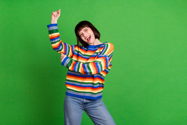 照片：一位年轻漂亮的女子，穿着休闲服，心情愉悦地跳舞，背景是绿色图片下载