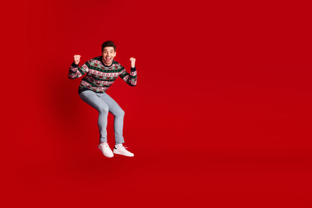 穿着节日毛衣，在喜庆的氛围中欣喜雀跃，这张充满活力的照片以大胆的红色背景为特色，非常适合用于假日品牌宣传和季节性广告图片下载