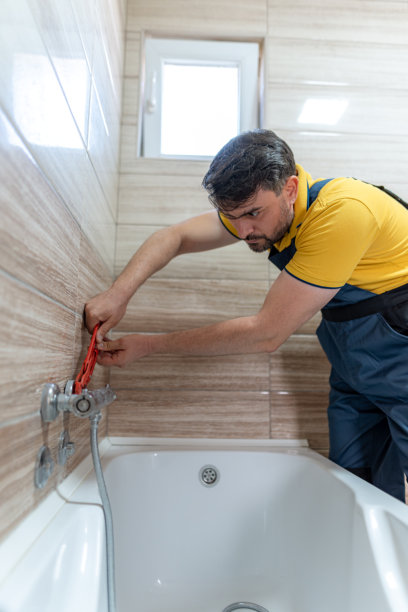 水管工在白天于现代浴室修理浴缸水龙头图片下载