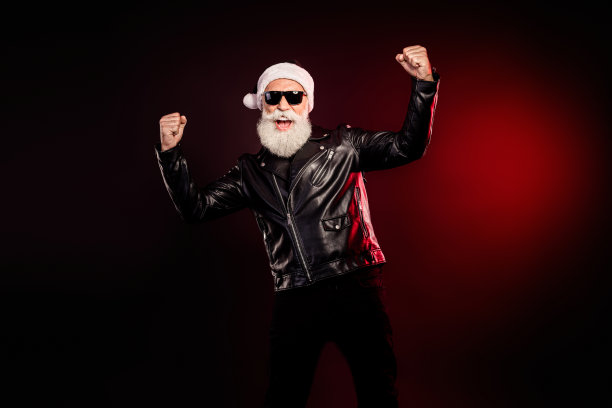 穿着皮夹克、留着胡须和戴着太阳镜的摇滚风圣诞老人，摆出充满活力的姿势，用于节日促销的素材照片图片下载
