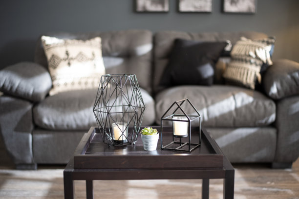 照片捕捉了摆放在小咖啡桌木质托盘上的现代深色几何烛台和多肉植物的特写细节。图片下载