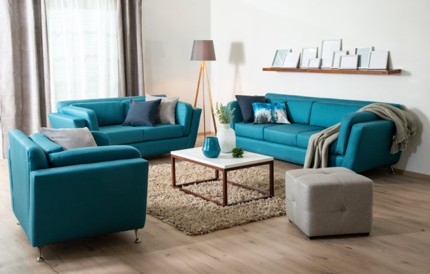 宽敞现代客厅内部照片，配有一整套鲜艳的蓝绿色沙发，围绕着现代白色大理石咖啡桌和长绒地毯布置。图片下载