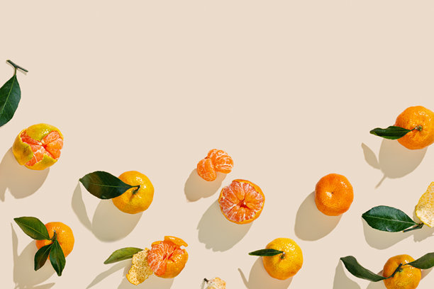 一套极简风格的橘子，新鲜的橙黄色水果，带有绿叶，置于米色背景上。柑橘类橘子，作为静物食物，俯视拍摄，夏日美学照片，留有复制空间。图片下载