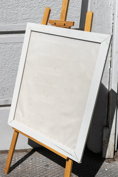 一个空白的画框立在街边的木质画架上，留有复制空间，适合设计师作为背景。竖幅照片。图片下载