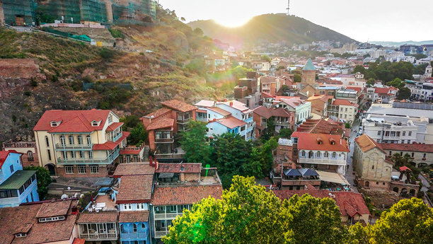 日落时分第比利斯老城的景观。空中缆车和远处的电视塔。图片下载