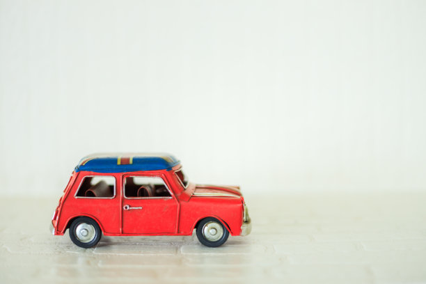 白色墙壁背景上的红色复古玩具车模型，迷你玩具车图片下载